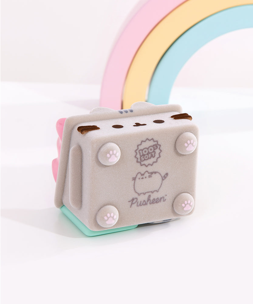 Dumpster Fire figure lays on its back to show the underside of the toy. On the bottom of the four legs are pink paw pad prints and the logos of the collaboration companies: 100% Soft and Pusheen the Cat.
