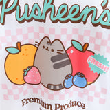 Close-up view of Pusheen fruits graphic tee. The multi-colored large front graphic features mint green, light pink, orange, blue, red, and brown. Included in the artwork is the phrase “100% Real Cute” in brown and a sticker badge that says “Fresh!” in mint green and pink. 