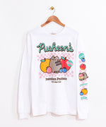 The Pusheen Fruits Long-Sleeve Tee hangs on a brown hanger in front of a white wall. The white unisex tee shirt features Pusheen the Cat surrounded by fruits including an orange, strawberry, apple, and a blueberry. The phrase “Pusheen’s Premium Produce” is printed above and below the checkered fruit graphic. The large front graphic is accompanied by fruit icons down the wearer’s left sleeve. 