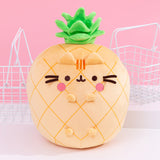 Front view of the Pusheen Fruits Scented Pineapple Squisheen Plush. Pusheen the Cat takes the form of a yellow pineapple. The yellow body of the plush has darker yellow grid lines that mimic the features of a pineapple. On the front of the plush are 3D versions of Pusheen’s ears and four paws. The yellow plush is topped with a vibrant green pineapple crown of leaves.  