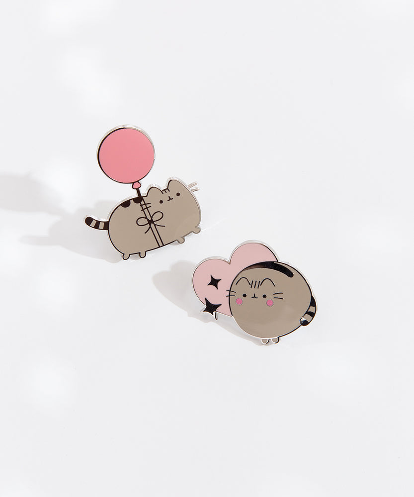 Close-up view of the Pusheen pins on a white background. The silver foil outline of the pins is hitting the light to show its reflective property. 