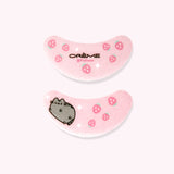 View of the patches in The Crème Shop x Pusheen Under Eye Patches - 3-pack. The light pink fiber patches have a graphic of Pusheen winking surrounded by white sparkles and pink strawberries on one patch. The other patch has a strawberry and sparkle pattern with The Creme Shop and Pusheen logos.