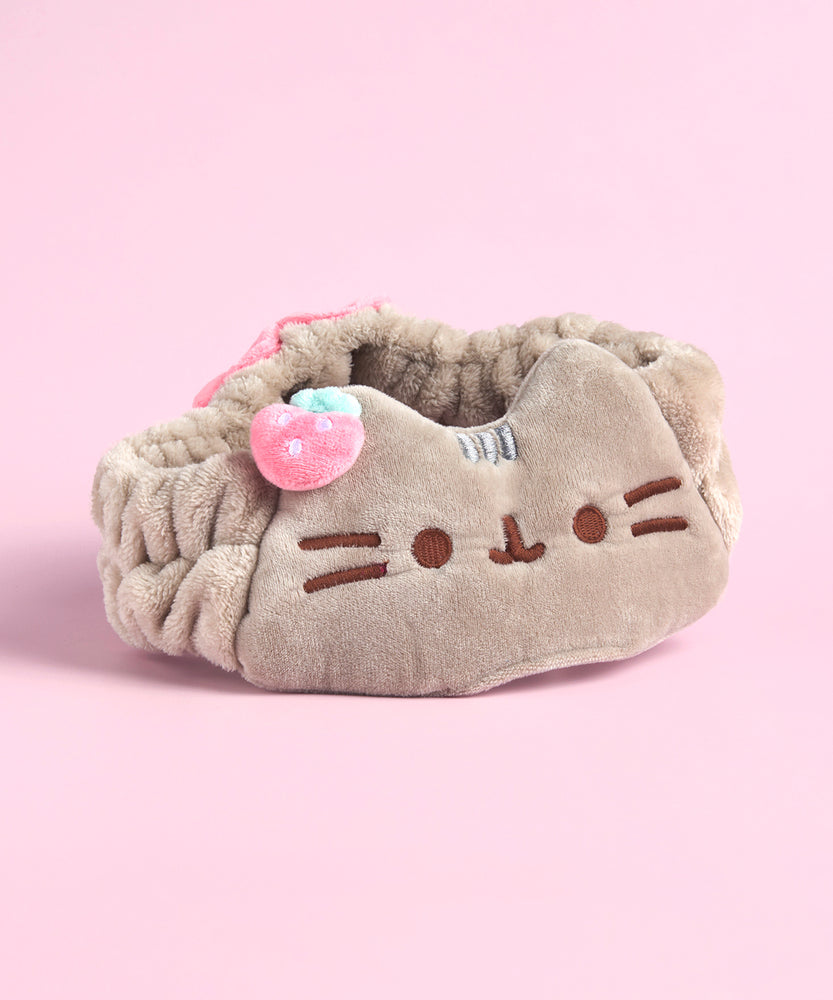 Front view of the Pusheen Spa Headband. The soft plush headband features Pusheen face embroidered in brown as well as a small plush strawberry.
