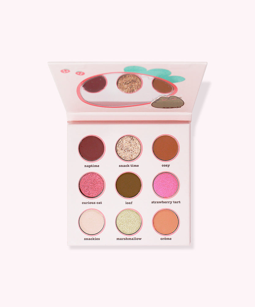 Interior view of the Pusheen eyeshadow palette. On the inside of the lip is a strawberry-shaped mirror for easy application. The eyeshadows include five matte shades, two shimmer shades, and two glitter shades.