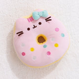 Full front view of Pusheen the Cat side of the reversisble Donut Plush. The strawberry glazed plush toy lays on a light white carpet surface.  
