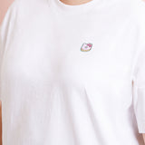 A model wearing a white shirt in a quarter view with the donut patch above the right breast. The patch makes the shirt look like an embroidered tee.