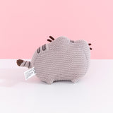 Back view of Knit Pusheen Plush. In this view, the front whiskers can be seen extending off the front of the plush. The plush sits atop little, crocheted paws. 