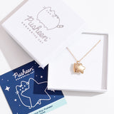 Gold vermeil finish of Pusheen Charm Necklace in its packaging. The necklace is placed inside a white box with a blue informational card. 