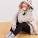 Model sitting on a wooden floor, wearing the Pusheen Character Hoodie with the hood pulled up. The model is smiling while daydreaming. 