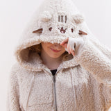 Close up of a model wearing the Pusheen Character Hoodie, smiling as they pull down the hood over their eyes. Pusheen's features are closer to the edge of the hood.
