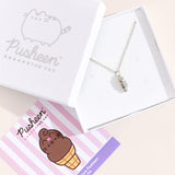 Sterling silver finish of Pusheen Dipped Cone Charm Necklace in its white packaging box. The necklace is hanging inside the white box with a pink, white, and purple informational card. 