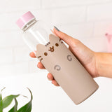Model holds water bottle to show size of glass bottle with pink top and grey silicone sleeve. 