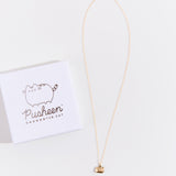 Full view of the gold charm necklace on top of a white background, the square jewelry box lid besides it.