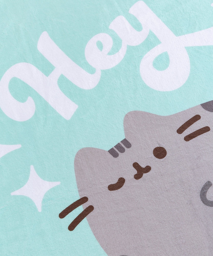 Close-up of the center graphic of the Hey Throw Blanket. The printed graphic shows Pusheen in her classic grey and brown colors with the phrase “hey” printed above in white.