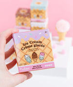 A close-up of the Pusheen Ice Cream Surprise Plush packaging. The front of the packaging has an ice cream cone inspired background with icing, sprinkles, and Pusheen Ice Cream characters in the foreground. The packaging says that these Surprise Plush are mini plush. 