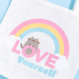 Close-up view of the printed graphic on the front of the rainbow Pusheen tote bag. The grey and brown tabby cat is sporting a light pink blush.  