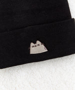 Close-up view of embroidered graphic on the Suspicious Pusheen Knit Hat. Pusheen looks with side eyes indicating her suspicious emotion. Pusheen is shown in her classic grey colors and brown whiskers. 