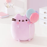 Front view of the Pusheen 15th Anniversary Squisheen Plush. The light purple cat holds a trio of balloons in her front paw while blushing.