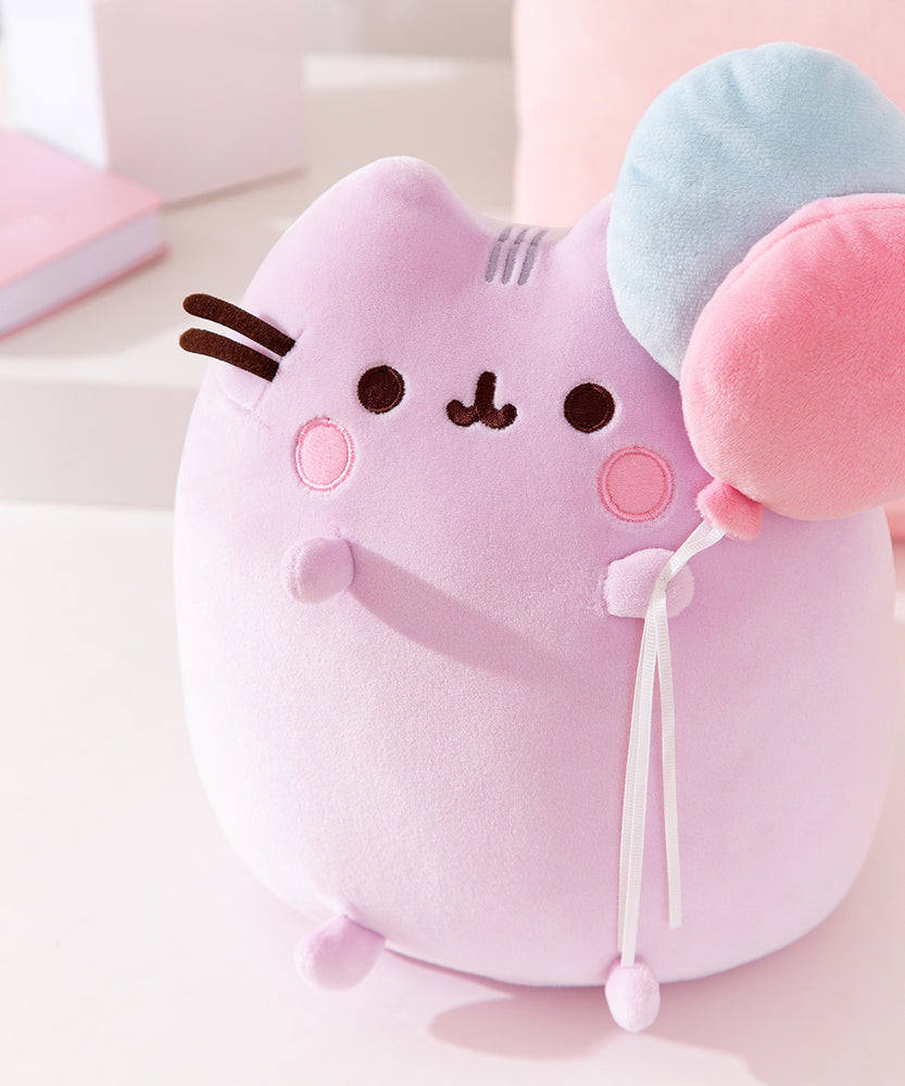 Close-up view of the Pusheen Anniversary Plush. Pusheen's facial features are embroidered on the front top of the sitting pose Squisheen plush.