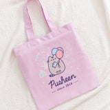 Front view of the Pusheen 15th Anniversary Tote Bag. The large graphic of Pusheen and a carnival take up most of the front of the purple canvas tote bag.