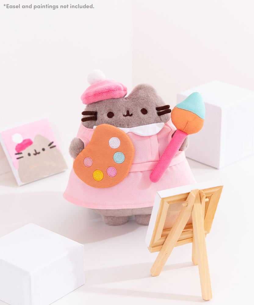 *Easel and paintings not included. Pusheen the Cat is dressed to paint in front of a small white canvas.