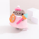 Quarter side view of the Artist Pusheen Plush. The pink smock that Pusheen the Cat wears has a white peter-pan style collar at the top of the smock. 