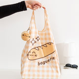 Model holds yellow gingham bag handle with Pusheen the Cat as a baguette bread graphic.