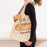 Model holds nylon bag on shoulder while showing off the attached baguette plush near the handle.