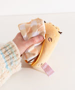 Model pulling yellow and golden brown gingham nylon bag out of a yellow plush container.