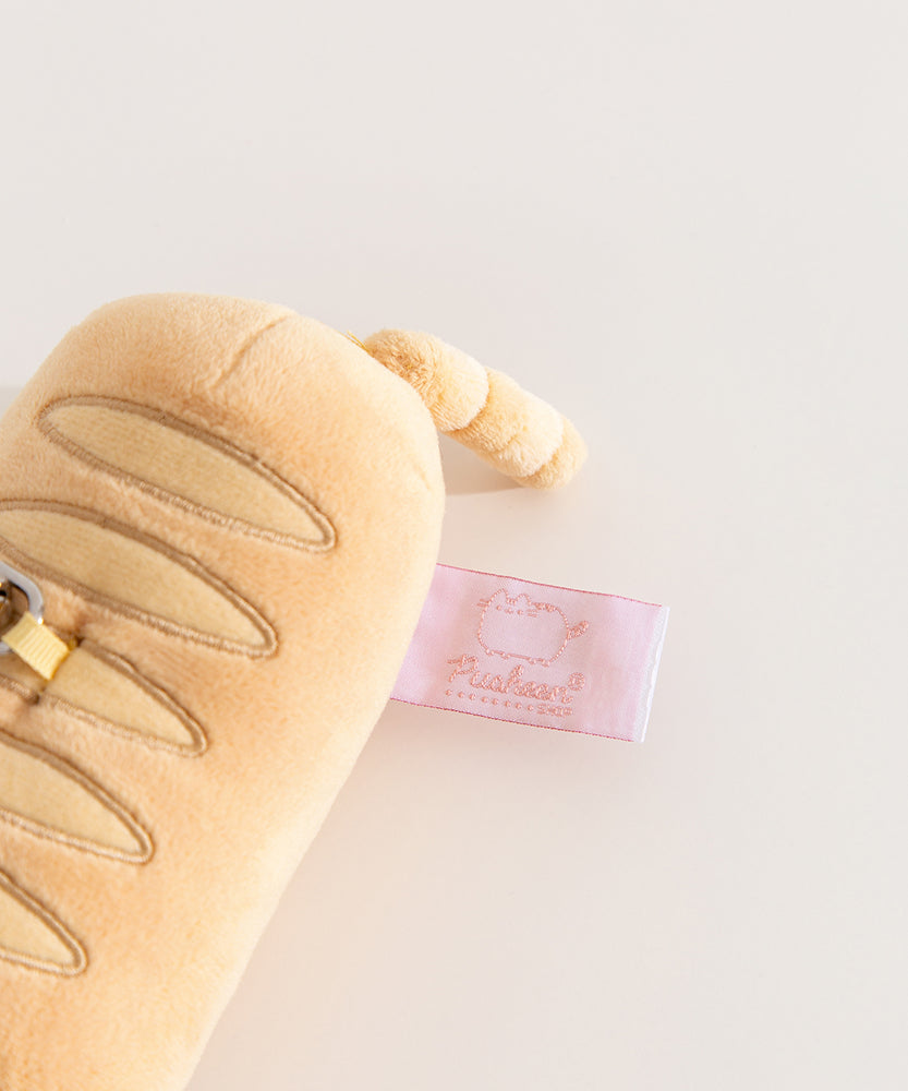 Close-up of the pink Pusheen Shop tag on the side of the Pusheen Baguette Reusable Bag Keychain Plush. 