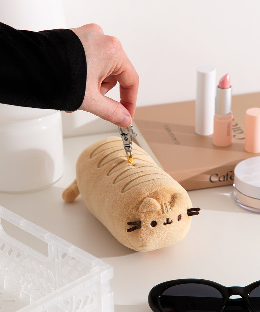 Model holds the lobster claw keychain that attaches to the top of the baguette plush bag holder. 