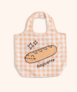 Yellow gingham nylon tote bag lies on a yellow surface. 