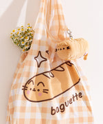 Yellow gingham print bag with a graphic of Pusheen the Cat as a baguette with the phrase "baguette" printed below.