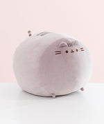 Side view of the front of the extra large squisheen plush of Pusheen. The rounded grey plush has two triangle shaped ears that extend off the top front of the plush.