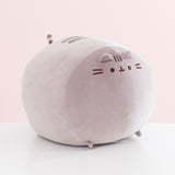 Side view of the front of the extra large squisheen plush of Pusheen. The rounded grey plush has two triangle shaped ears that extend off the top front of the plush.