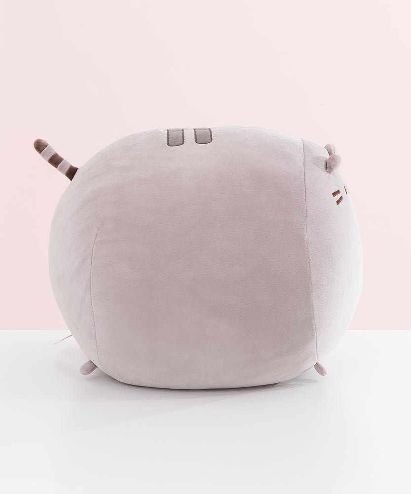 Side view of the grey cat plush. The rounded shape has a slightly flatter front face to showcase Pusheen's face.