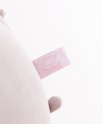 Close-up view of the Pusheen Shop logo tag that is affixed near the bottom of the jumbo grey plush.