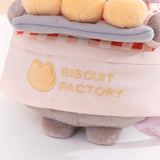 Close-up view of the apron Pusheen wears that says, “Biscuit Factory” accompanied by a cat outline logo. 