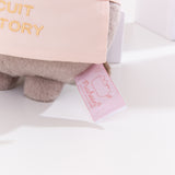 Close-up view of white and pink Pusheen Shop logo tag on the baker plush. 