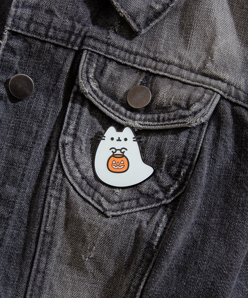 Close-up view of Boosheen-themed pin pinned on a distressed black denim jacket. The ghost-shaped pin is pinned to the front pocket of jacket to show the scale of the pin. 