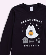 Close-up view of large front graphic on the center of the Boosheen Halloween Pusheen long-sleeve tee. Above and below the ghost and spooky scene are the words “Paranormal Society” printed in white. 