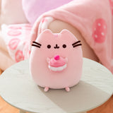 Front view of the Cherry Macaron Squisheen. The pink plush shows Pusheen the cat holding a multi-pink cherry macaron in her front paws.