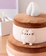 Close-up of the Pusheen plush on the Cake Squisheen. Pusheen's eyes, nose, and whiskers are embroidered in black while her three head stripes are a medium brown embroidery color.