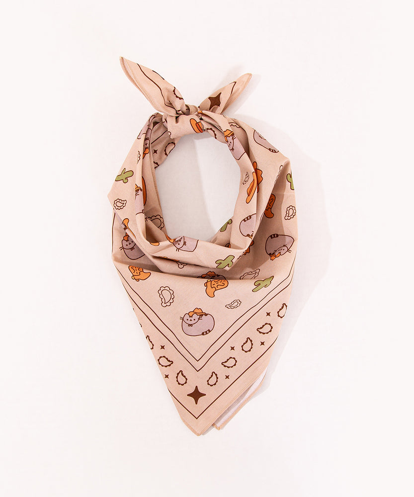 Cowboy Pusheen Bandana folded at a neck scarf. The light brown scarf has graphics of stars, paisley, catci, cowboy boots, and pusheen the cat wearing a cowboy hat.