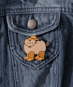 Pusheen cowboy pin attached to dark denim jacket.