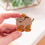 Model holds the Cowboy Pusheen Boots Deluxe Pin to show the scale of the cat-shaped pin with gold plated outline details.