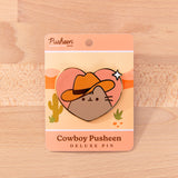 Pusheen the Cat wears a brown cowboy hat and smiles. Pusheen's classic whiskers and head stripes are present on this pin.