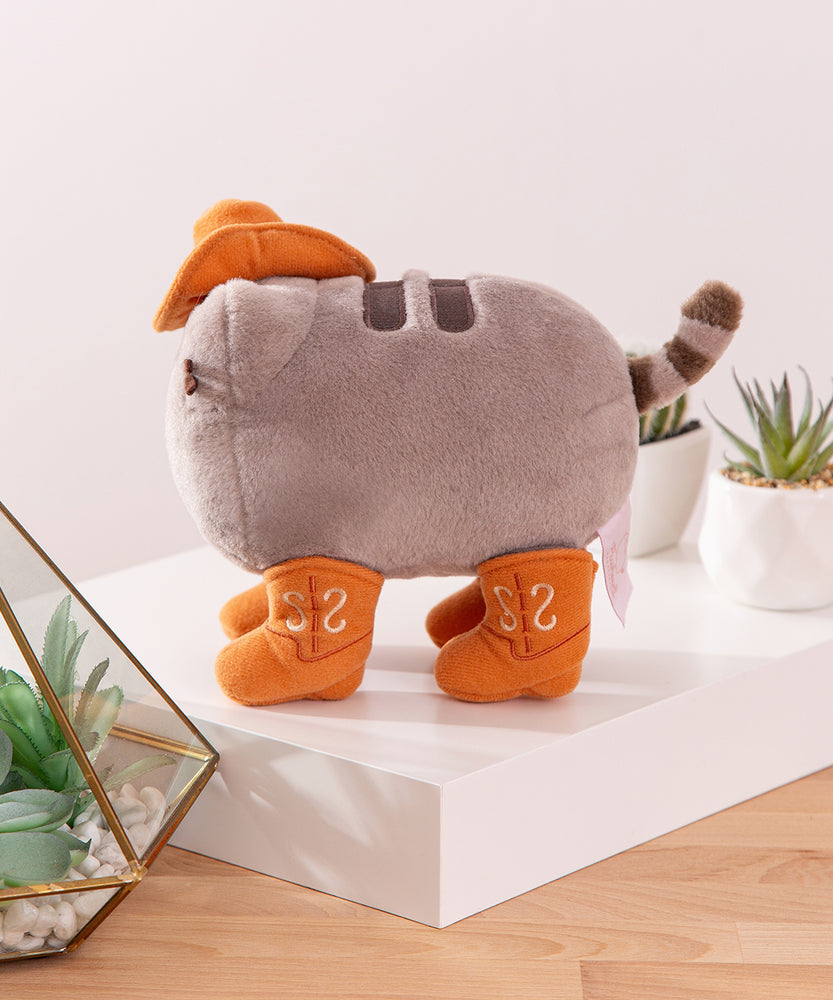 Side view of the fuzzy grey cat plush. Pusheen's striped tail extends off the back of the plush with a slight curve.