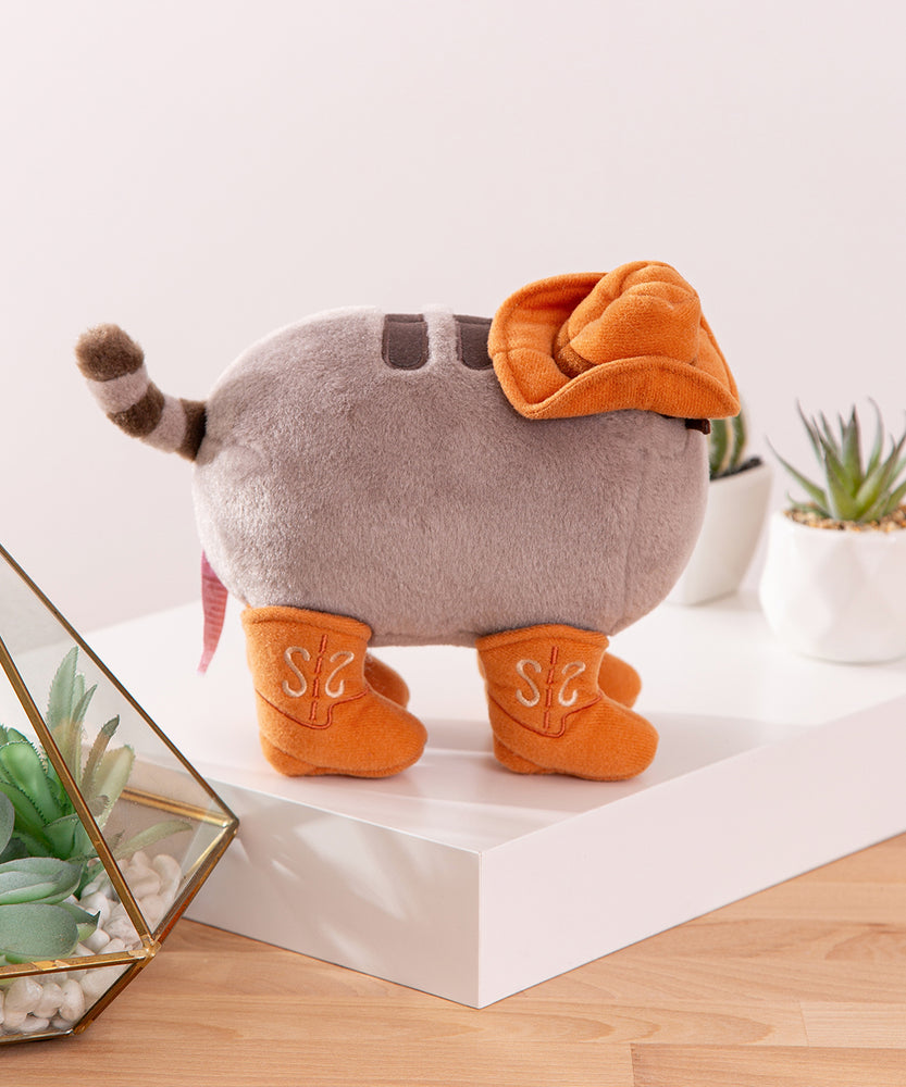 Side view of the Pusheen Cowboy Plush. The miniature cowboy hat covers a portion of Pusheen's head and back. 