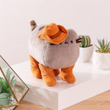 Side quarter view of the Cowboy plush. The cowboy hat is attached to Pusheen's ear and slightly covers her eye and whiskers.